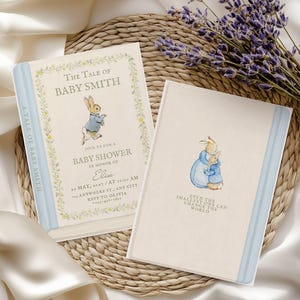 May include: Two rectangular baby shower invitation cards featuring watercolour illustrations of rabbits in blue jackets. The left card reads The Tale of Baby Smith, and the right card features two rabbits hugging with the text Even the smallest one can change the world.