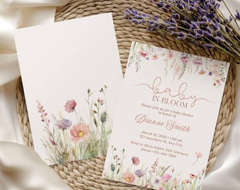 May include: Baby shower invitations with floral watercolor designs. The invitations feature the text "baby in bloom" and event details. The design includes pink, purple, and green floral elements, with a sprig of lavender.