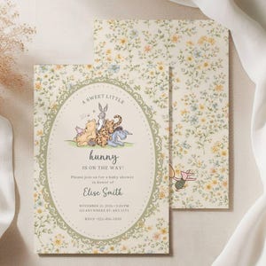 May include: Baby shower invitation featuring Winnie the Pooh characters. The invitation has a floral background and an oval frame with the text "A Sweet Little Hunny is on the Way!" and event details. The back of the invitation has a floral pattern.