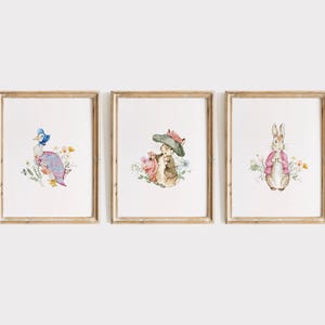 May include: Three framed watercolor prints featuring charming animal illustrations. The prints depict a duck, a rabbit, and a squirrel, each surrounded by floral elements. The frames are a light brown color, adding a classic touch to the artwork. The overall theme is a whimsical, vintage aesthetic.