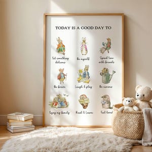Op de afbeelding: Een ingelijste print met de tekst "TODAY IS A GOOD DAY TO" en illustraties van dieren met positieve affirmaties. De print staat in een houten lijst en wordt tentoongesteld in de buurt van een gevlochten mand met knuffels.