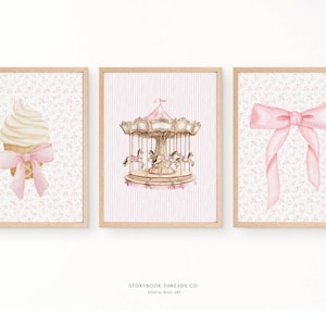 May include: Three framed watercolour prints. The left print shows an ice cream cone with a pink bow. The centre print depicts a carousel with horses. The right print displays a pink bow. All prints have a floral background.