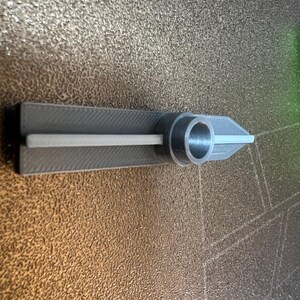May include: A gray 3D printed tool with a round hole in the center and a slot running along the length of the tool.