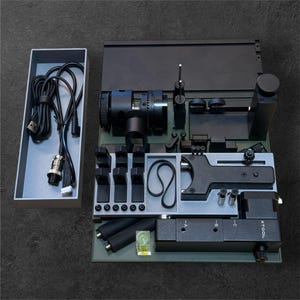 May include: A black and gray 3D printing tool kit with a variety of tools and accessories. The kit includes a camera, a belt, a level, and a variety of other tools. The kit is organized in a gray tray with a black and gray base. The kit is labeled "XTOOL".