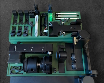 May include: A green tool box with black tools and accessories. The box has a label that says "XTOOL" on the side. The tools include a small motor, a gear, a belt, and a variety of screws and other small parts.