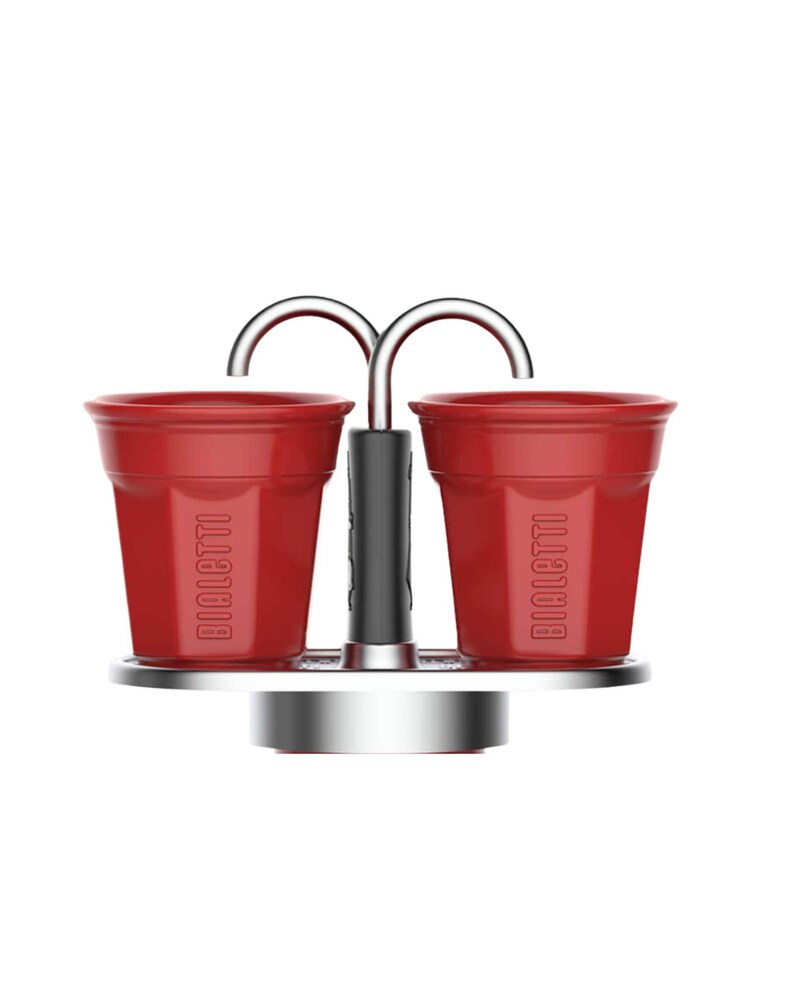 Może przedstawiać: Czerwony zestaw filiżanek do espresso Bialetti ze srebrnym metalowym stojakiem i uchwytem. Filiżanki są cylindryczne z logo Bialetti wydrukowanym z boku. Uchwyt jest czarny, a stojak okrągły.