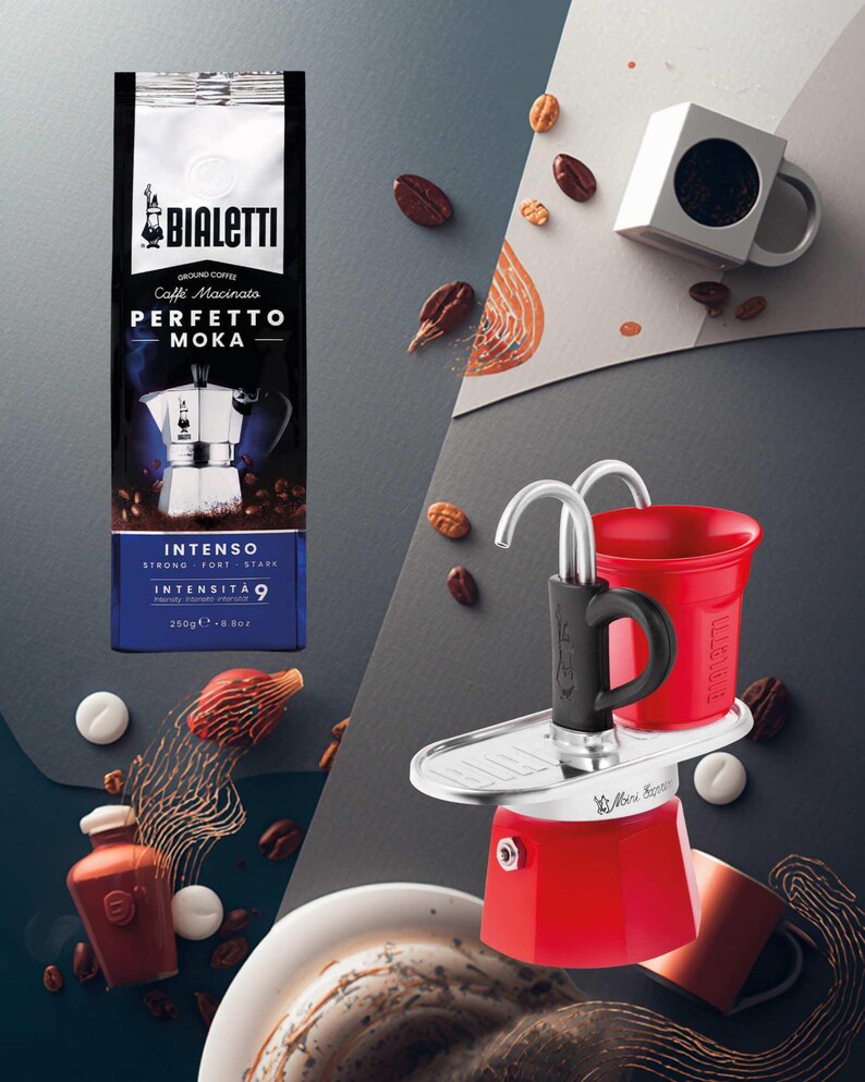 Może przedstawiać: Zdjęcie produktu przedstawiające czerwony ekspres do kawy, paczkę kawy mielonej i czerwony kubek. Na opakowaniu kawy widnieje napis "PERFETTO MOKA" i "INTENSO 9". Ziarna kawy i białe cukierki są rozrzucone.