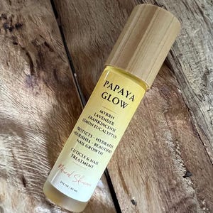 May include: A bottle of Papaya Glow cuticle and nail treatment with a wooden cap. The label lists ingredients like myrrh, lavender, and lemon eucalyptus. The bottle is 3 fl oz.