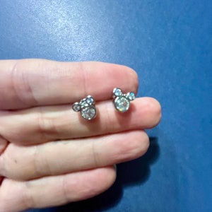 May include: A pair of silver stud earrings with a Mickey Mouse design featuring clear rhinestones.