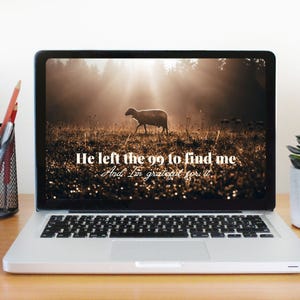 May include: A laptop computer with a desktop background of a field with a single sheep walking through it. The sun is shining through the trees in the background. The text on the screen reads "He left the 99 to find me. And I'm grateful for it."