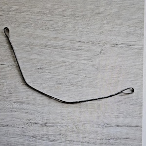 Puede incluir: Una cuerda de arco negra para un arco y flechas. La cuerda de arco está hecha de un material delgado y duradero y tiene dos bucles en los extremos.