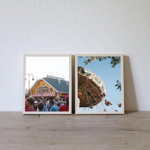 May include: Two framed photographs, one showing a crowd of people in front of a building with the words "Cookies" on the sign, and the other showing a carousel ride against a blue sky.