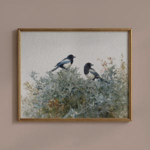 Puede incluir: Impresión enmarcada con dos urracas posadas en un arbusto frondoso. Las aves tienen plumaje blanco y negro con alas azules. La obra de arte está enmarcada en un marco dorado.