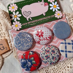 May include: A set of six round fabric-covered buttons with various floral and geometric patterns in red, blue, and white. A business card with a pig illustration and the text "www.vintagepolkadotpig.etsy.com" is also visible.