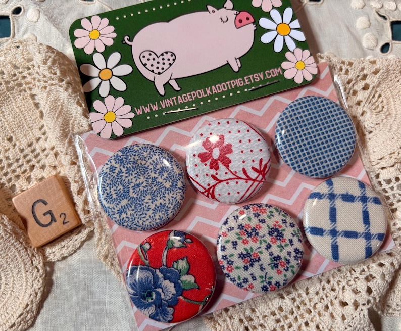 May include: A set of six round fabric-covered buttons with various floral and geometric patterns in red, blue, and white. A business card with a pig illustration and the text "www.vintagepolkadotpig.etsy.com" is also visible.
