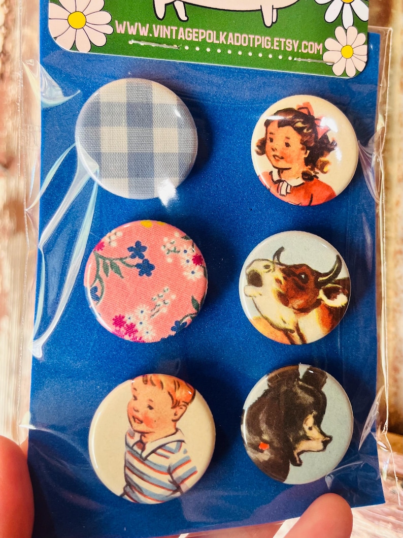 May include: A set of six round vintage-style pinback buttons. Designs include a blue and white gingham pattern, a girl in a red dress, a pink floral pattern, a cow, a boy in a striped shirt, and a bear. The top of the package has the text "WWW.VINTAGEPOLKADOTPIG.ETSY.COM".