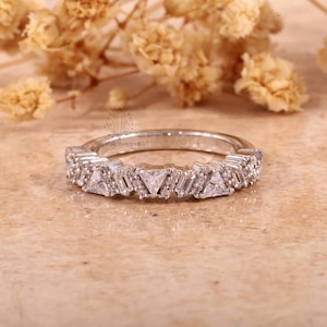 May include: A delicate silver band ring with a row of small, sparkling diamonds. The diamonds are set in a graduated pattern, with larger diamonds in the center and smaller diamonds on the sides. The ring is a beautiful and elegant piece of jewelry.