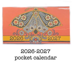 May include: A 2026-2027 pocket calendar with an orange background and a decorative moth design. The moth has a detailed pattern with yellow, white, and blue floral elements. The calendar has a yellow band with the years 2026 and 2027.