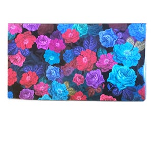 May include: A rectangular fabric piece featuring a dense floral pattern of roses in vibrant shades of bright pink, magenta, purple, and electric blue set against a solid black background, interspersed with dark green and metallic gold leaves.