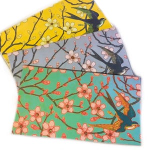 May include: A set of three ceramic mugs with a speckled, matte finish. The mugs are in shades of cream, light gray, and dark gray. Each mug has a simple, minimalist design and a rounded handle.