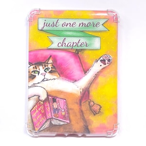 May include: A clear phone case featuring a whimsical illustration of a cat reading a book. The cat is lounging on a pink pillow with the text "just one more chapter" above. The background is yellow.