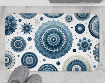 May include: A white bath mat with a blue and white mandala pattern. The mat features a variety of different sized mandalas, all with intricate details.