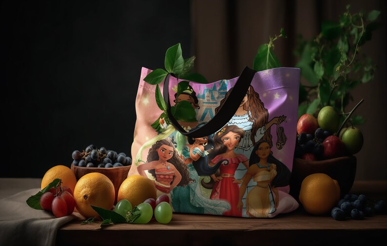 Pu&ograve; includere: Una borsa tote rosa con un'illustrazione colorata di principesse Disney. La borsa ha manici neri e uno sfondo rosa e viola con stelle. Le principesse indossano abiti colorati e hanno i capelli lunghi. La borsa &egrave; appoggiata su un tavolo di legno con frutta e uva.