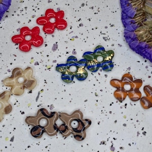 Peut inclure: Assortiment de boucles d'oreilles en résine en forme de fleur de différentes couleurs, motifs et designs. Les boucles d'oreilles sont dans les tons rouge, bleu, vert, marron et blanc.