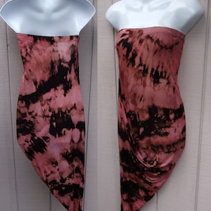 May include: A strapless, tie-dye dress in shades of pink and black. The fabric is soft and flowing, with a unique pattern. The dress is displayed on a white mannequin, showcasing its shape and design. The dress is a versatile piece for various occasions.