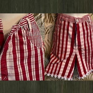 May include: Red and white striped shorts and a matching top with silver buttons. The shorts have a white lace trim along the bottom hem. The top has a pocket and a button closure.