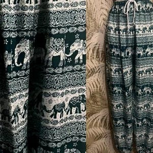 May include: Dark teal and white patterned pants with an elephant motif. The pants have a drawstring waist and a relaxed fit. The fabric features rows of elephants and decorative borders.