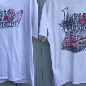 May include: Two white t-shirts featuring a racing theme. One shirt displays "Jeff 24 Gordon" in red and gray lettering. The other shirt has a graphic of a red race car with the number 24 and the name "Jeff Gordon".
