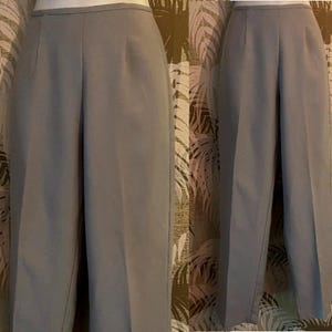 May include: A pair of light gray, high-waisted trousers. The pants have a straight leg design and feature a front pleat. The fabric appears to be a lightweight material, suitable for warmer weather. The trousers are displayed on a mannequin.