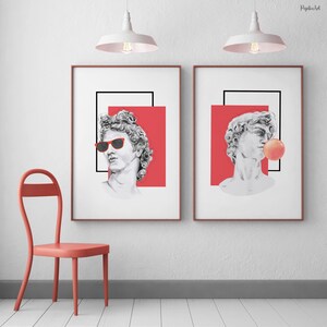 Puede incluir: Dos impresiones enmarcadas de un busto de escultura clásica con un toque moderno. El busto de la izquierda lleva gafas de sol rojas, mientras que el busto de la derecha sopla una burbuja rosa.