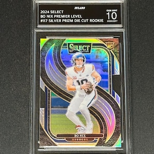 May include: A 2024 Select Bo Nix Premier Level #117 Silver Prizm die-cut rookie football card in a protective slab. The card features a holographic finish, a player in a white uniform holding a football, and the text Bo Nix Broncos.