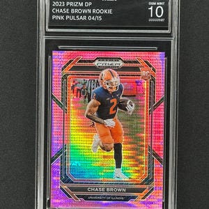 May include: A graded trading card of Chase Brown, a football player for the University of Illinois, in a pink, blue, and green color scheme. The card is labeled "2023 Prizm DP Chase Brown Rookie Pink Pulsar 04/15" and "Gem Mint 10".
