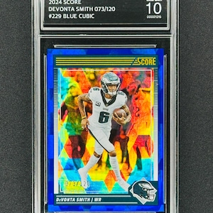 Puede incluir: Una tarjeta de intercambio clasificada de Devonta Smith, un receptor abierto de los Philadelphia Eagles, en un patrón de mosaico azul, amarillo y rojo. La tarjeta está numerada 073/120 y está clasificada como Gem Mint 10.