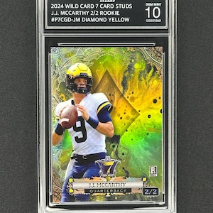 May include: A graded sports trading card featuring J.J. McCarthy, a quarterback, in a football uniform. The card is labeled "2024 Wild Card 7 Card Studs" and "2/2 Rookie." The card is graded Gem Mint 10 and has a diamond yellow background.