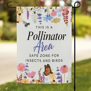 Könnte beinhalten: Eine weiße Gartenflagge mit dem Text "THIS IS A Pollinator Area SAFE ZONE FOR INSECTS AND BIRDS." Die Flagge ist mit bunten Blumen, Schmetterlingen und Bienen verziert. Die Flagge hängt an einem schwarzen Metallständer.