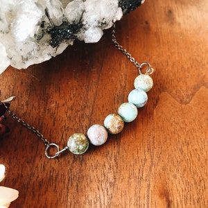 May include: A silver chain necklace with a row of six turquoise and brown gemstone beads.