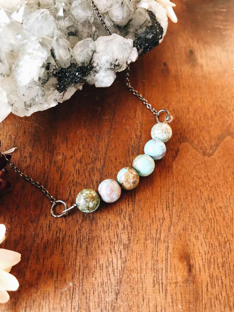 May include: A silver chain necklace with a row of six turquoise and brown gemstone beads.