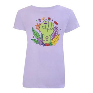 K&ouml;nnte beinhalten: Ein hellviolettes T-Shirt mit einer erhobenen gr&uuml;nen Faust. Die Faust h&auml;lt eine Blume und hat ein weibliches Symbol am Handgelenk. Die Faust ist von bunten Blumen und Bl&auml;ttern umgeben.