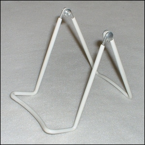 May include: White metal display stand with two adjustable legs. The stand is designed to hold a plate or other flat object.