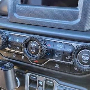 May include: Close-up of a car's dashboard with four round knobs. The knobs are black with a tire tread pattern and have various labels, including "AUTO", "OFF", "TUNE", "BROWSE", and "ENTER".