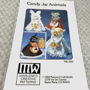 May include: A craft pattern packet titled Candy Jar Animals by Marlene's Creative Patterns, MW 509. The cover features illustrations of four stuffed animals dressed in clothing, including a cat, a rabbit, a mouse, and a bear, each holding a basket.