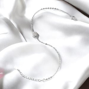 May include: A delicate silver chain bracelet with a single round clear crystal.
