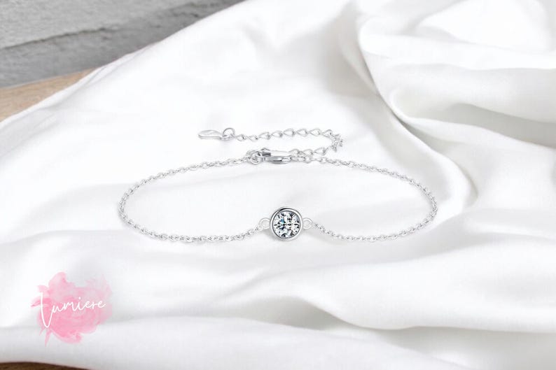 May include: A delicate silver chain bracelet with a single round clear stone in the center.
