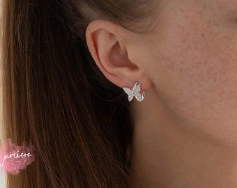 May include: Silver butterfly hoop earrings with clear cubic zirconia stones.