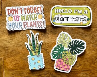 May include: Four stickers with a plant theme. One sticker says "Don't forget to water your plants!" with two smiley faces. Another sticker says "Hello I'm a plant mama" with a smiley face. The last two stickers are illustrations of potted plants.