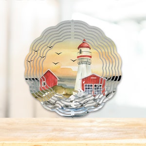 May include: A metal wind spinner with a layered design featuring a lighthouse, a red house, and seagulls against a sunset background.